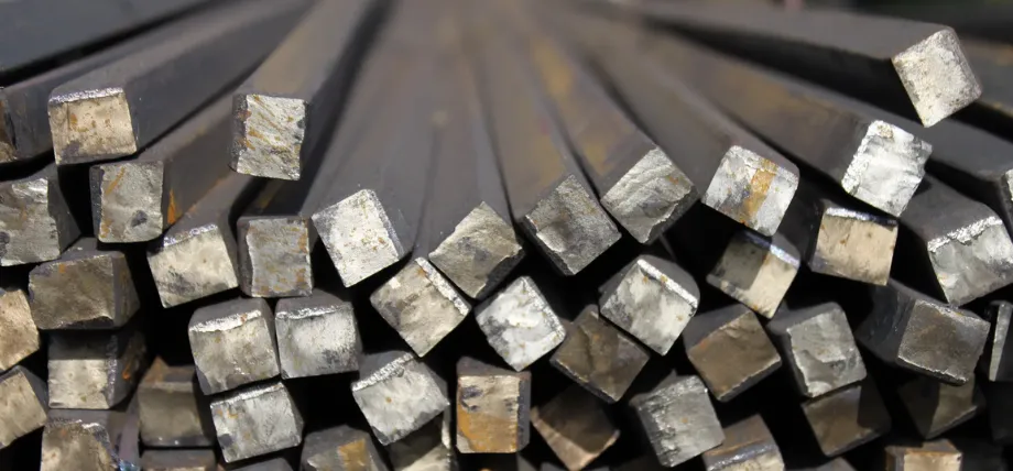 A stacked bundle of square-cross-section steel bars with metallic surfaces showing mill scale