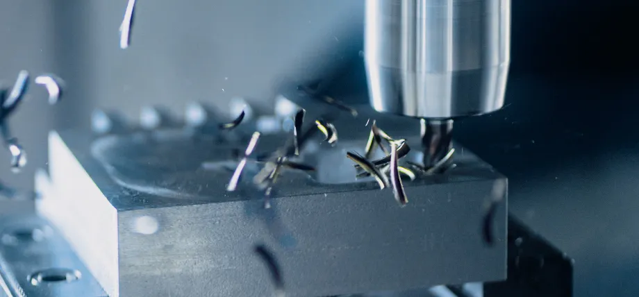 Close-up of a CNC milling machine in operation, with a rotating cutting tool removing material from a metal workpiece