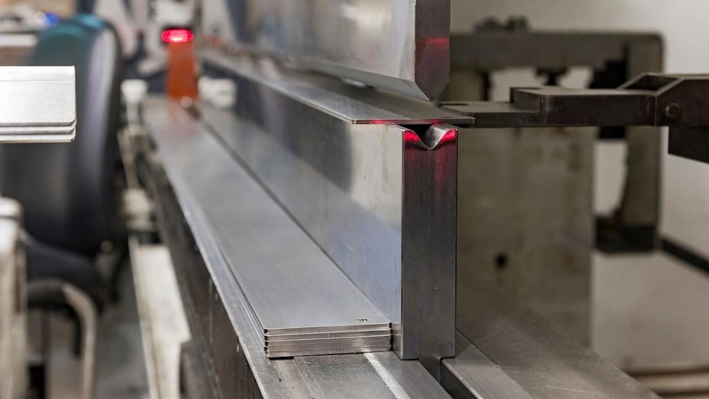 A close-up view of a sheet metal forming setup with a die and press