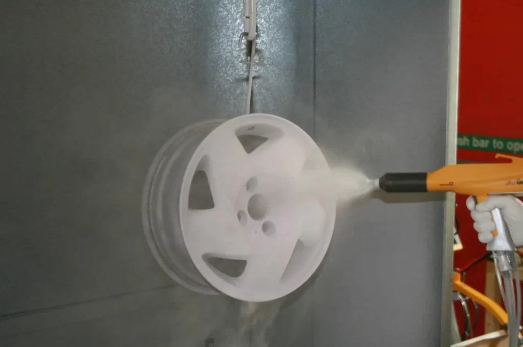 The image shows an alloy wheel being powder-coated
