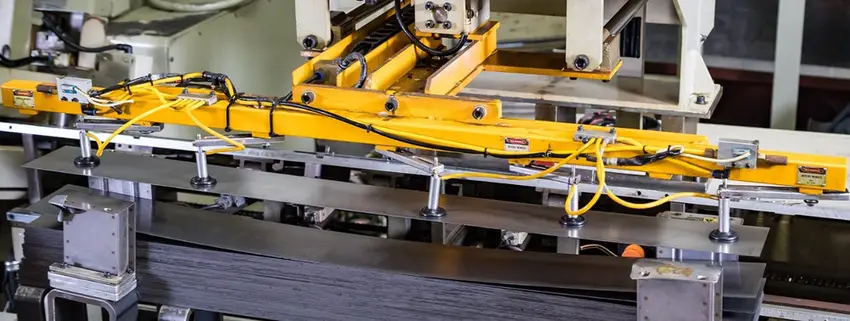 Aluminum strips being fed through an automated stamping press