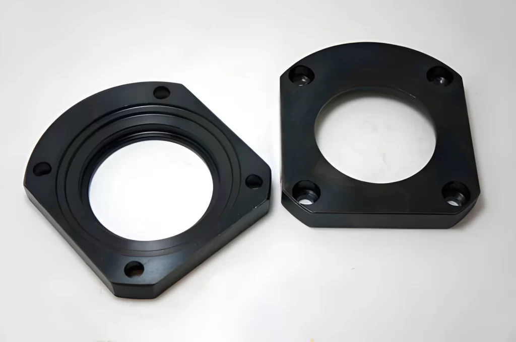 The image shows a steel face flange manufactured using CNC machining and finished with a black oxide coating.
