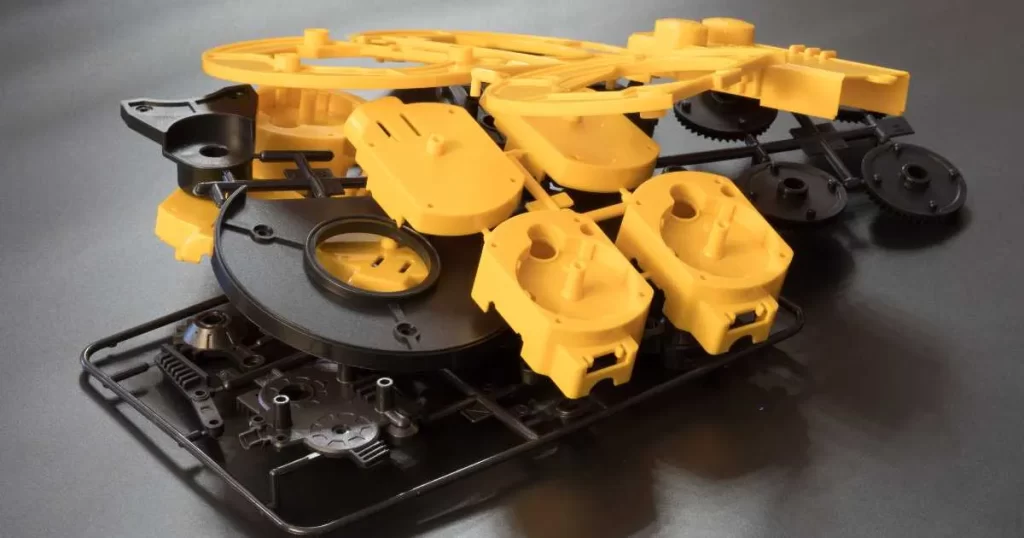 Injection-molded plastic parts in yellow and black are still attached to the runner system
