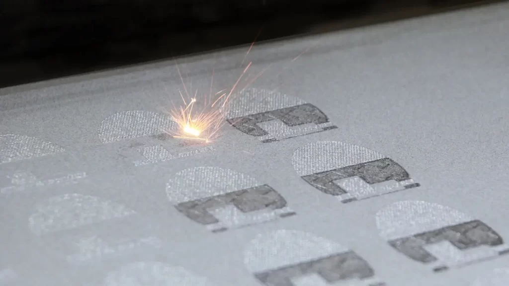 The image depicts the Direct Metal Laser Sintering (DMLS) process, where a high-powered laser selectively fuses metal powder layer by layer to create a solid component.