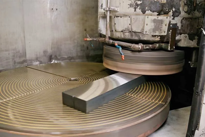 A close-up view of Blanchard grinding two casting stocks over a rotating table