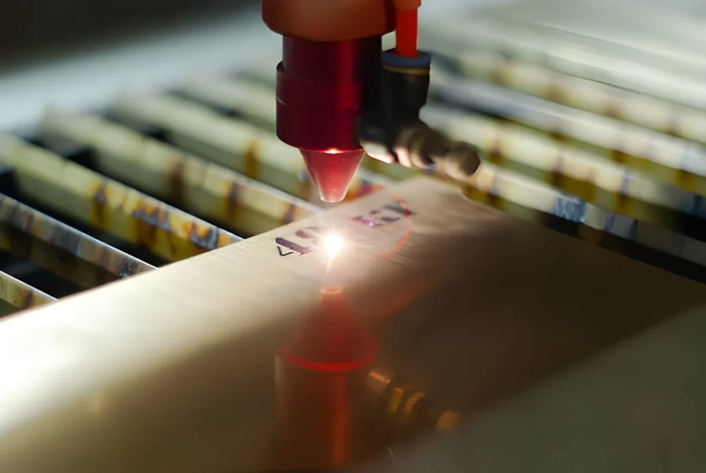 The image shows a close-up of a laser engraving process, with precise etching being applied to a metal surface.