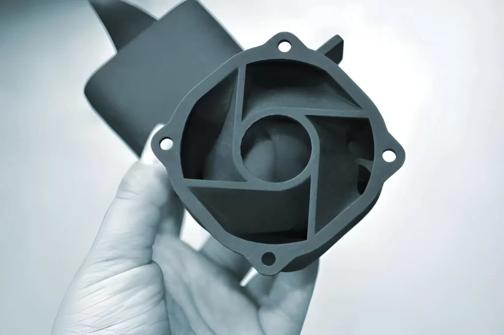 The image shows a person holding a 3D printed object made from polyamide powder using the Multi Jet Fusion (MJF) process.