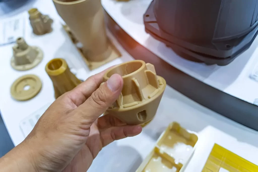 A person holding and showing several PEEK injection molded aerospace parts.