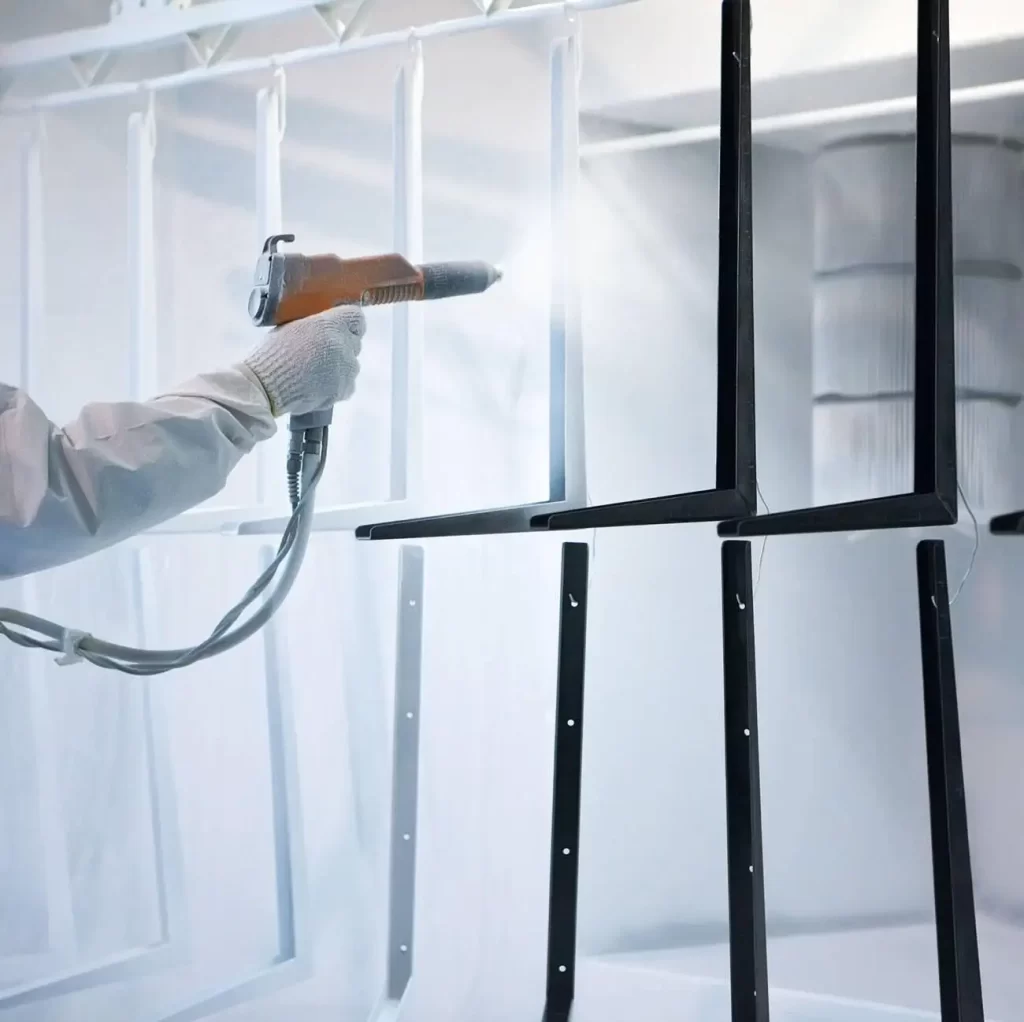 The image shows metal parts hanging at an angle during the powder coating process.