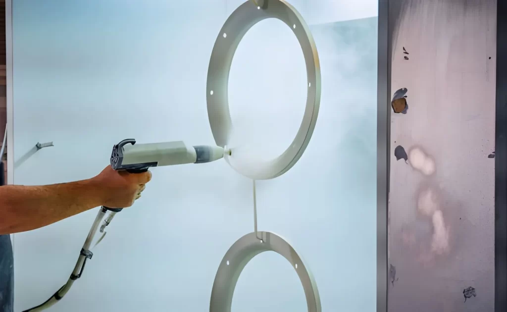Worker powder coating a metal ring surface finish
