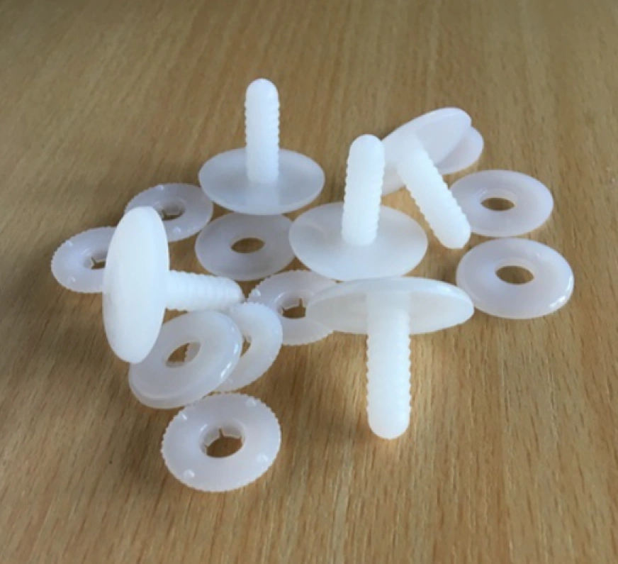 Small white injection-molded plastic toy safety joints with washers on a wooden surface.
