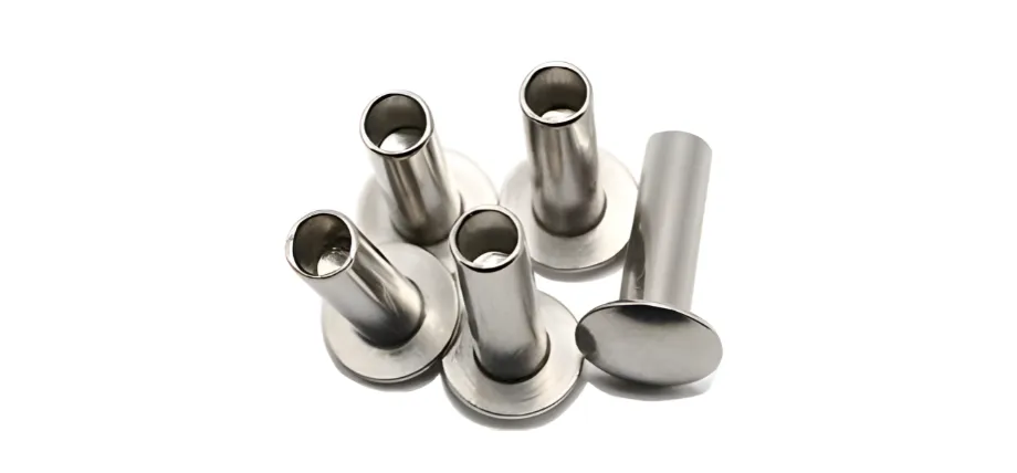 Group of uninstalled metallic tubular rivets, primarily with flat flange heads and hollow shanks designed for rolling or flaring during installation.