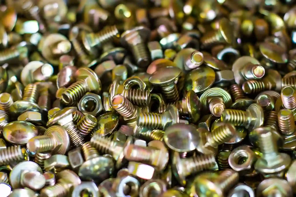 The image showing a collection of zinc-plated nuts and screws with yellow chromate coating.