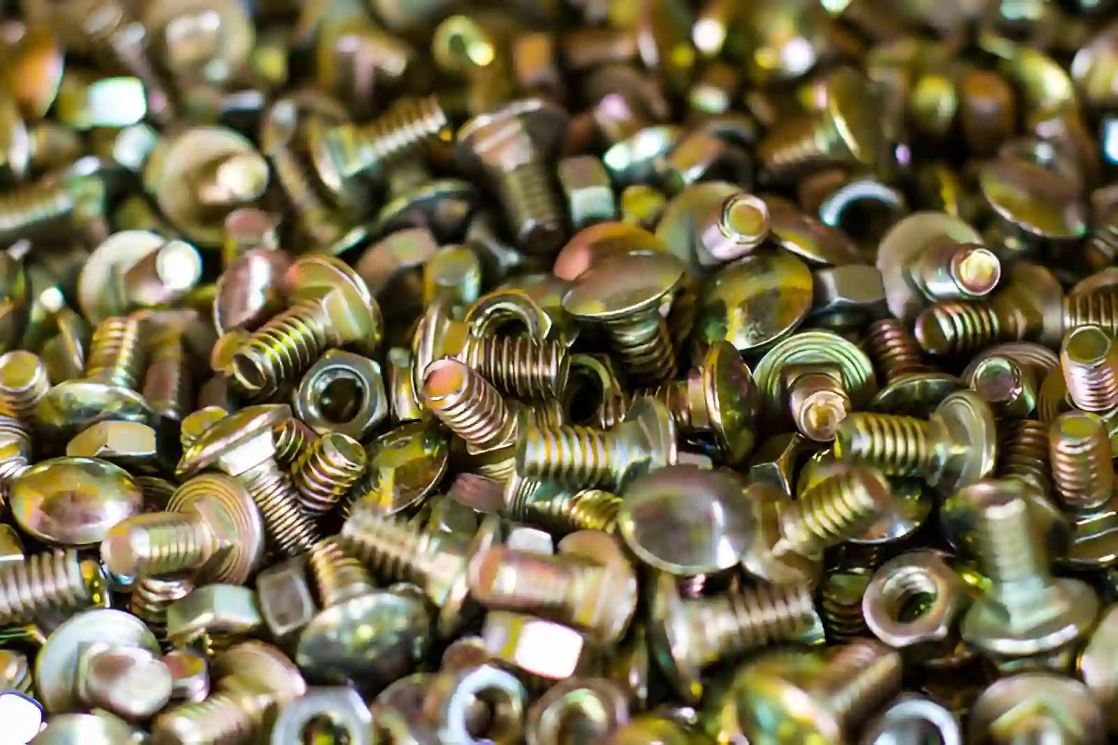 A dense pile of steel screws with a bright gold iridescent yellow chromate conversion coating on every thread