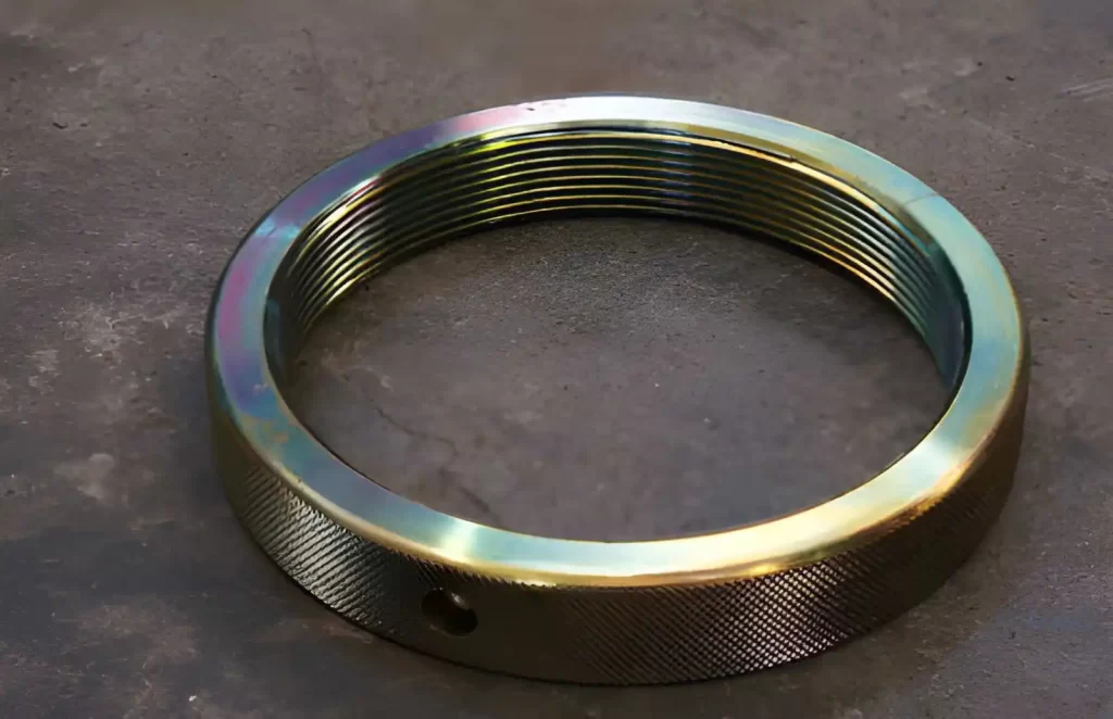 The image shows CNC-machined thread ring parts with a zinc-plated surface finish placed on the floor.