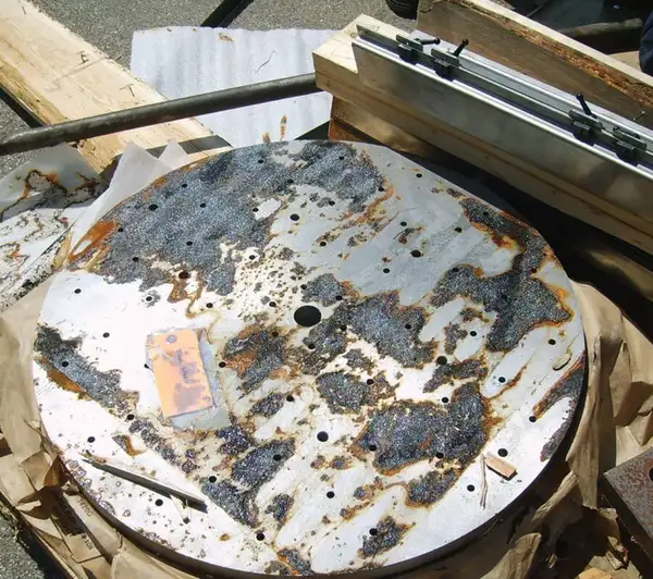 Circular metal plate with extensive black rust