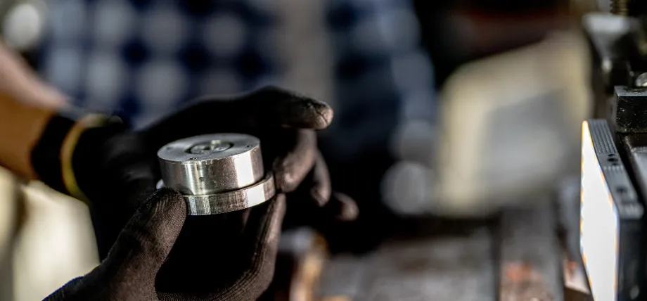 Gloved machinist inspecting a precision cnc machined carbon steel part