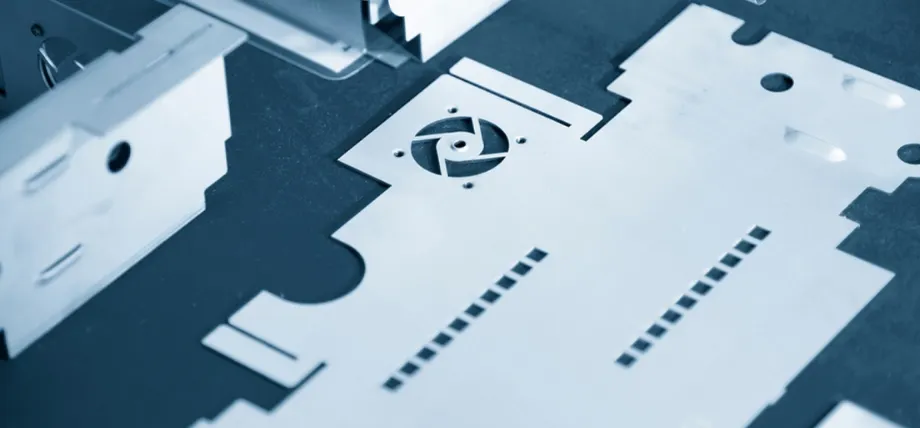 Close-up of laser-cut sheet metal parts with precise ventilation slots, fan cutout, mounting holes, and folded edges ready for enclosure assembly.