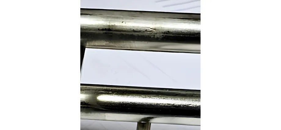 A close-up view of two parallel, cylindrical metal bars showing rough, imperfect weld joints and surface discoloration on a white background.