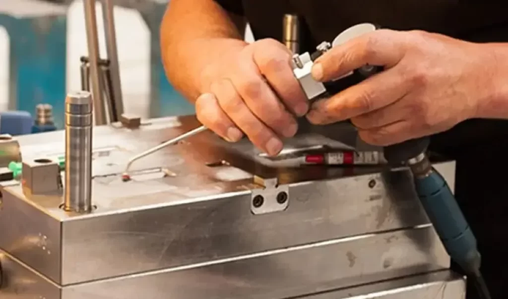 Technician performing hands-on maintenance on an injection mold to prevent short shot defects.