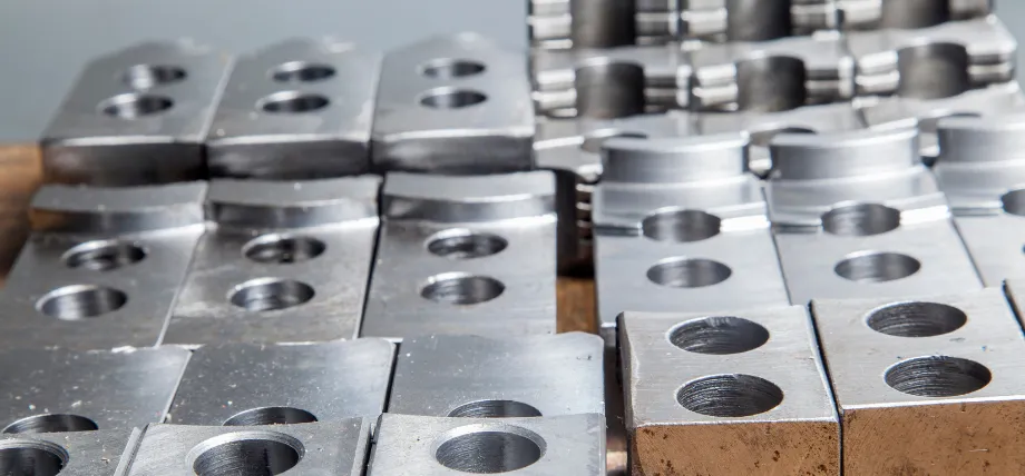 Multiple precision-machined 4140 alloy steel parts with drilled and tapped holes arranged in stacks, showcasing uniform silver finish and complex geometries typical of 4140 alloy steel machined parts.