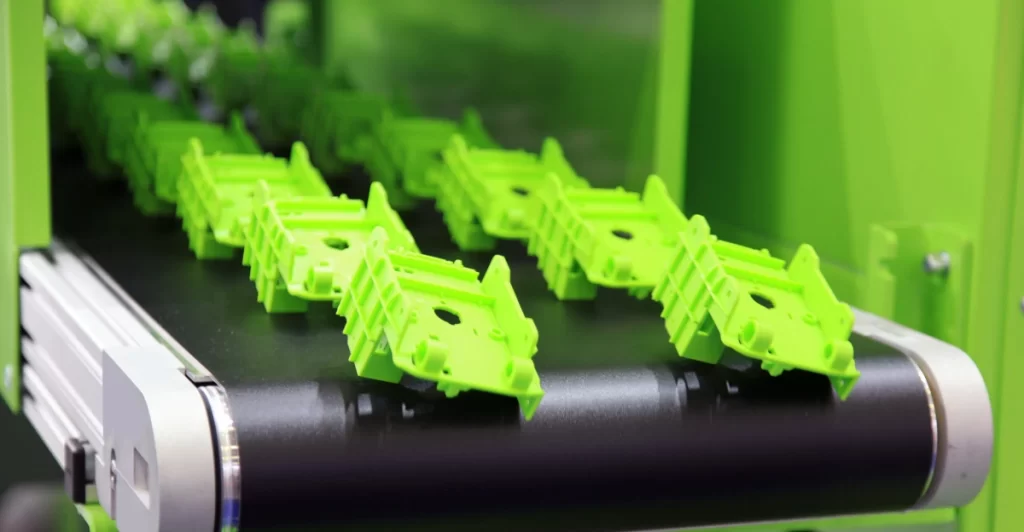 Green injection-molded plastic prototypes on a conveyor belt