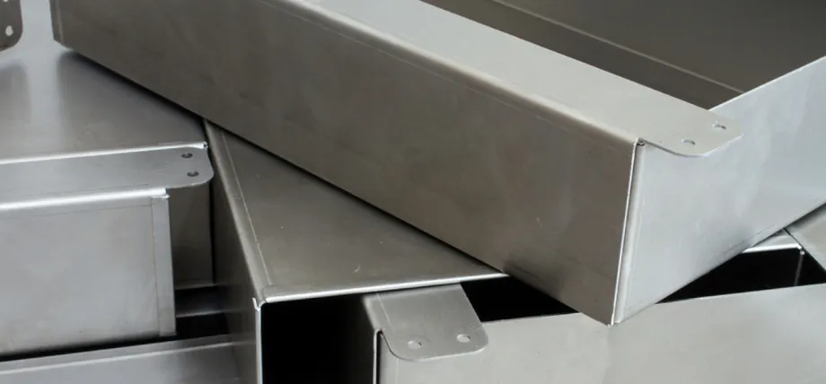 Stack of completed anodized aluminum sheet metal enclosures with folded flanges and mounting tabs