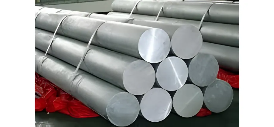 A stack of large-diameter, silver aluminum logs bundled together with white straps in an industrial setting.