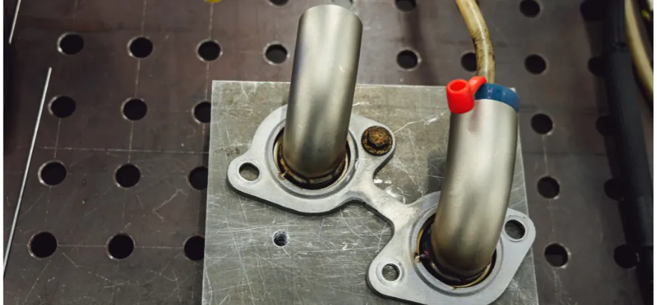 Fabricated assembly featuring two elbow tubes welded to a shared flange on a work surface