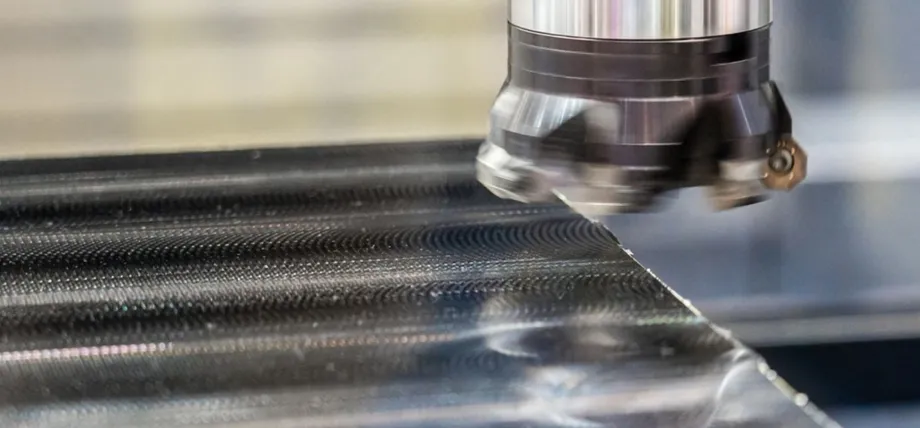 Close-up of a high-speed face milling cutter leaving a distinct overlapping circular tool path pattern on a metal surface.