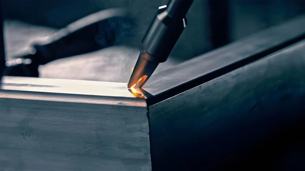 A close-up view of an aluminum welding torch positioned over a joint.