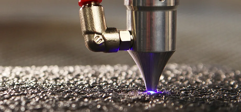 Close-up of a laser cutting machine precisely engraving or cutting a textured metal surface.
