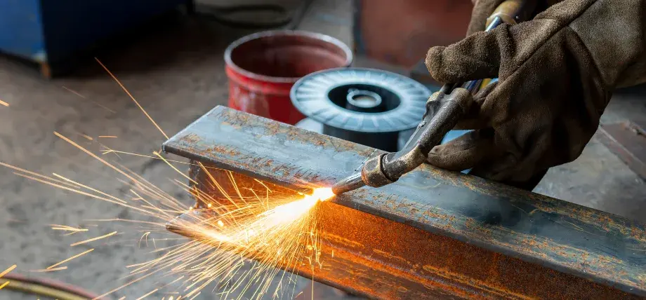 Hand holding a gas laser cutter on a steel structure support