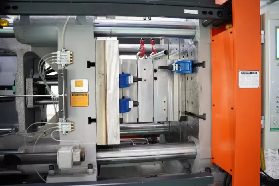 Industrial injection molding machine with open mold showing clamping unit and hydraulic components