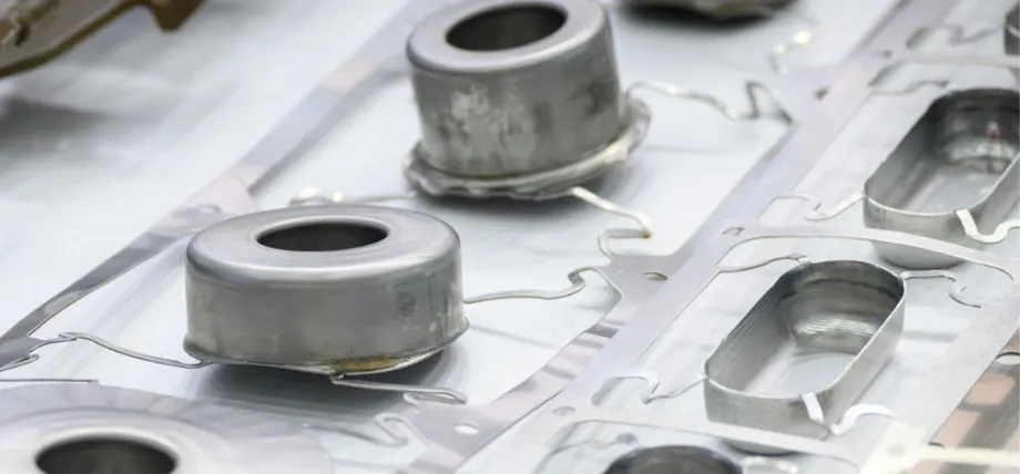 Close-up of laser-cut stainless steel parts with cylindrical components attached to a flat sheet