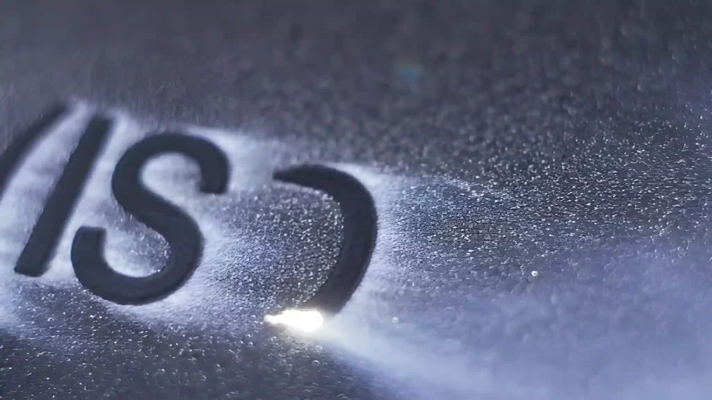 A laser engraver etches text codes onto a metal surface for identification and traceability.