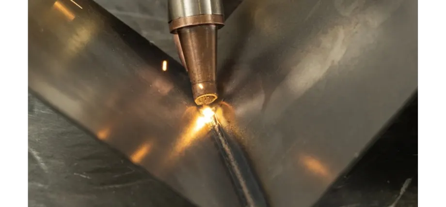 Laser welding torch emitting a bright spark while fusing two polished metal sheets