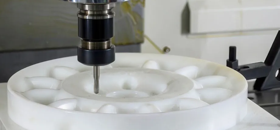 A CNC mill precisely machining a large, white circular nylon gear component to achieve tight tolerances.