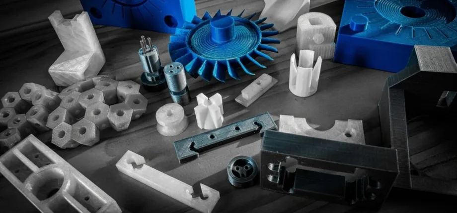An assortment of 3D-printed and molded plastic parts in various colors and geometries spread across a workbench.