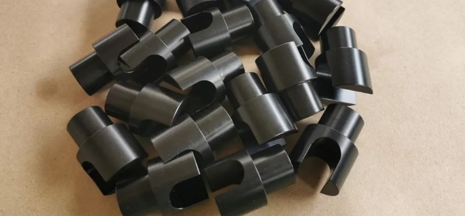 A collection of small, precision-machined black POM plastic bushings with a smooth, low-friction surface finish