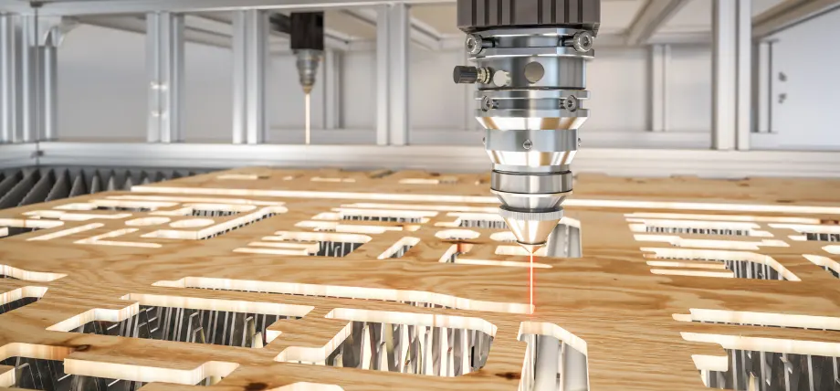 Laser cutting machine head emitting a red beam, cutting intricate patterns into a wooden sheet.