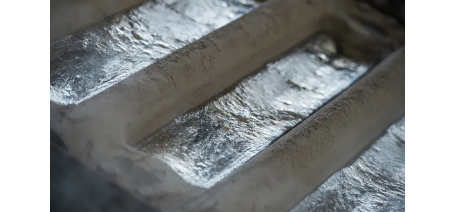 Several large, raw aluminum ingots resting in a casting mold, showing their rough metallic surface.