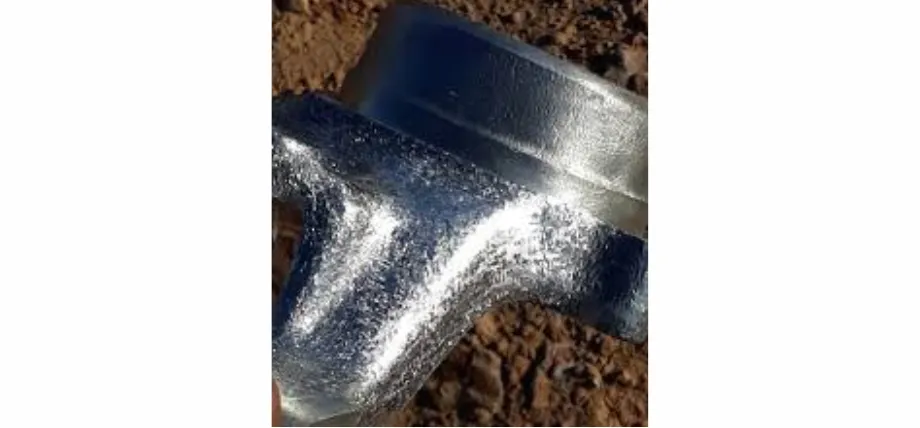 Close-up of a cast aluminum component showing a rough, pitted surface texture alongside a smooth machined edge.