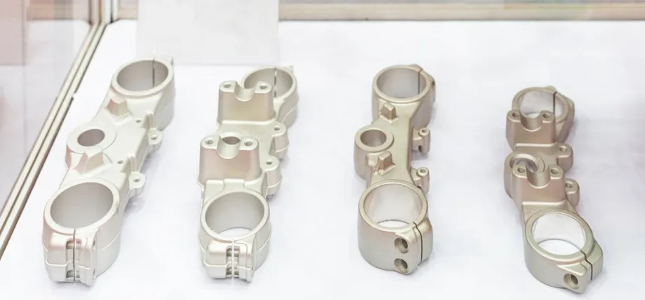 Four identical cast aluminum mechanical brackets with a smooth, sandblasted finish are displayed on a white surface.