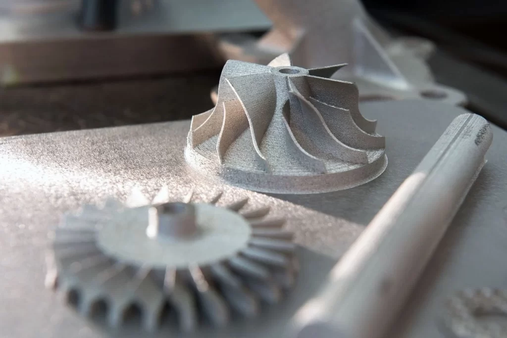 Freshly printed metal impeller and gear parts on a build plate
