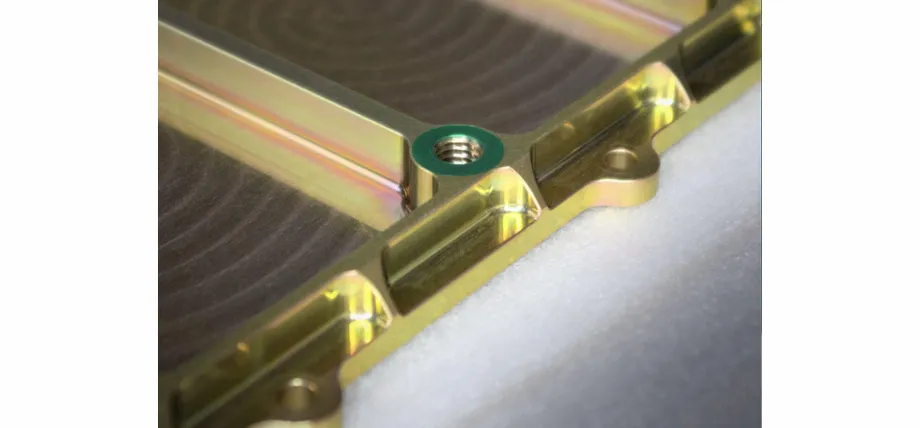 A high-precision machined aerospace housing with a MIL-DTL compliant gold Alodine coating and visible concentric milling marks.
