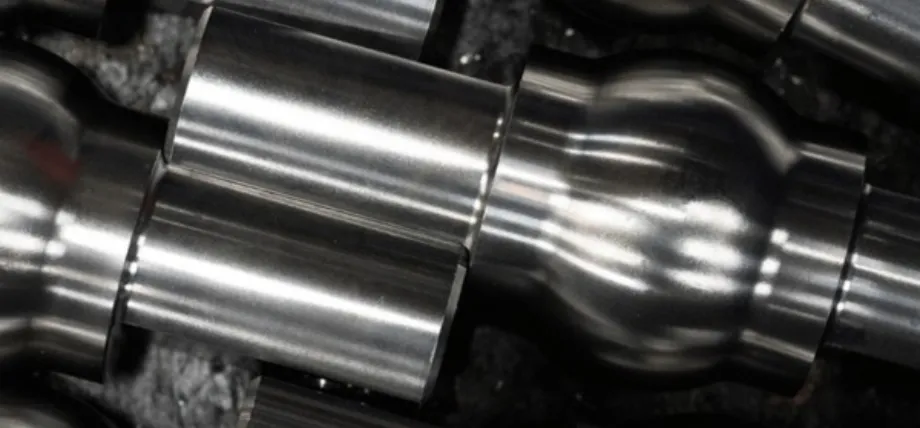 Close-up of industrial metal components with a high-shine, reflective polished surface showing smooth contours and highlights.