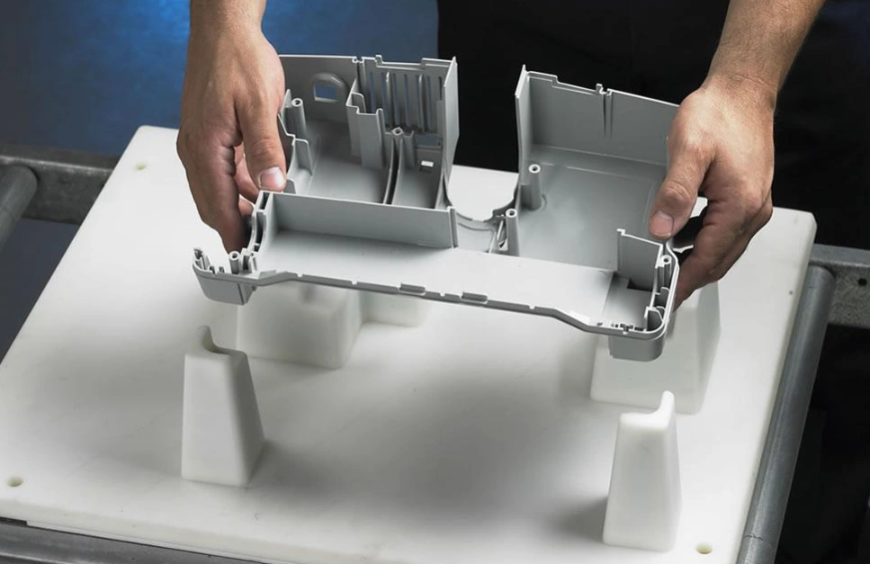 Hands positioning gray plastic part onto white 3D printed jig with support blocks