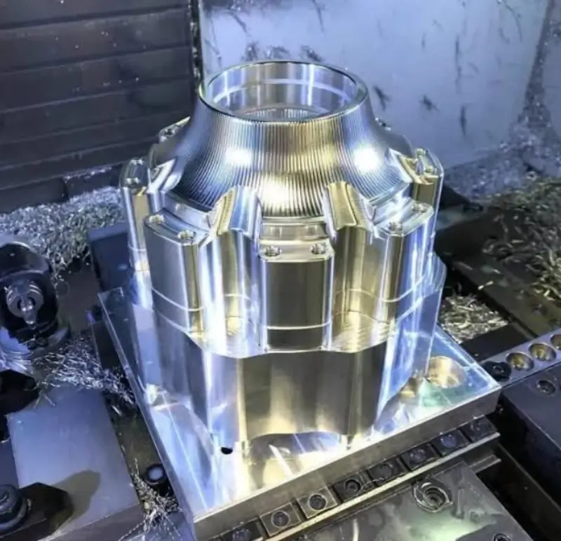 Freshly CNC-machined metal prototype part clamped on machine bed with shavings around it