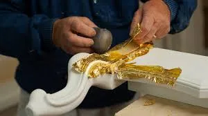 A man working on gold leaf, giving it a shape
